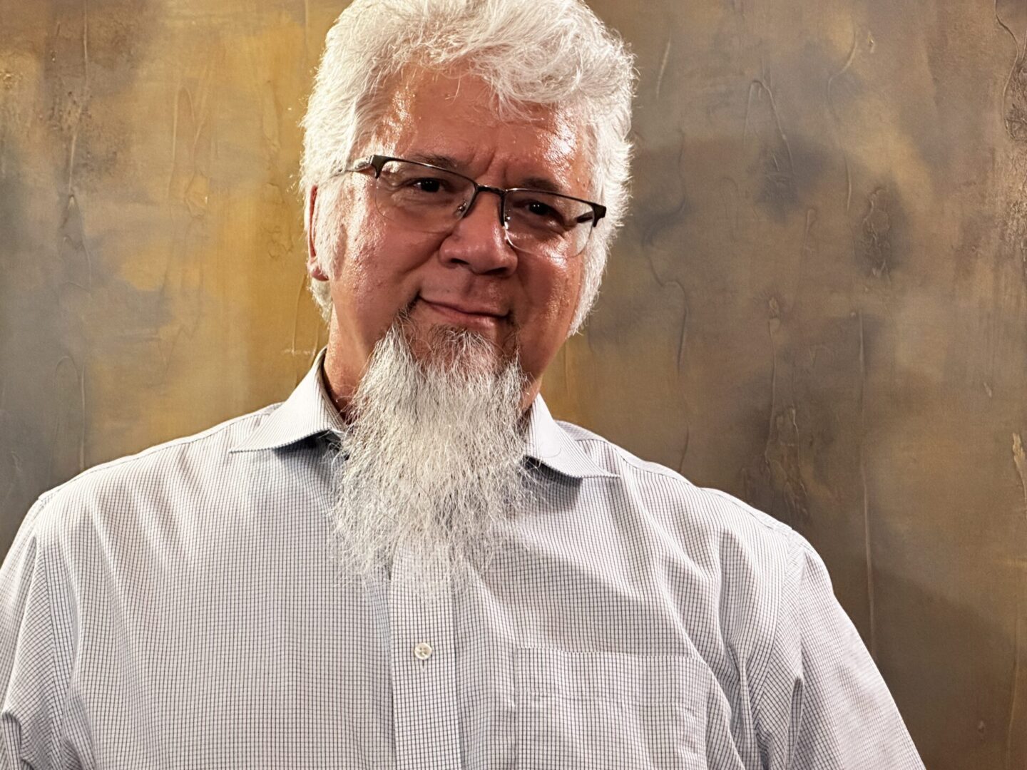 A man with white hair and glasses is wearing a shirt.