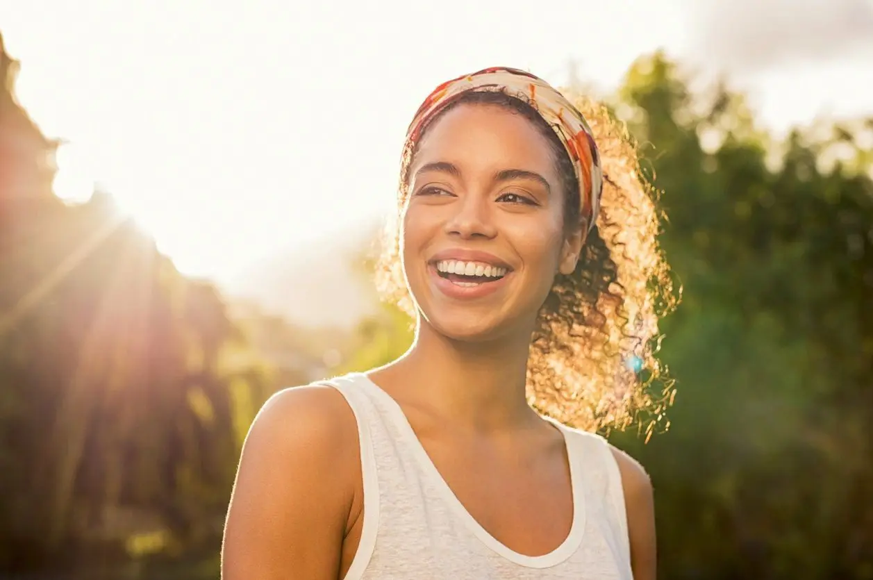 A woman smiling with trees in the background